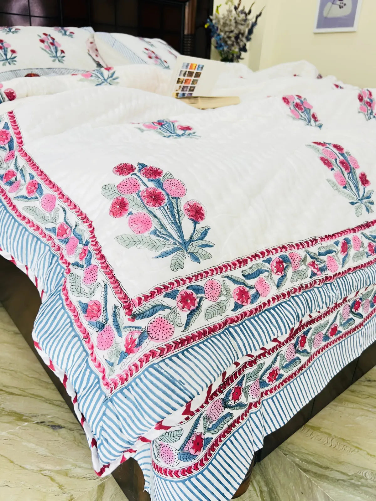 Floral embroidered quilt on a bed with a striped pattern