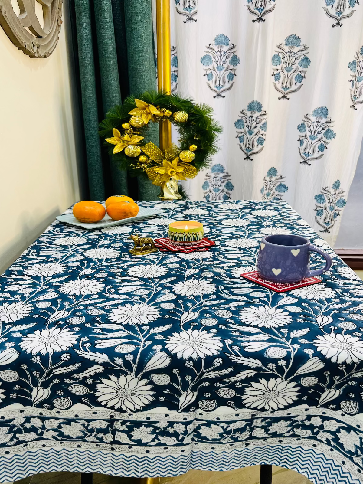 Tablecloth with floral pattern on a table set with fruits and a vase.