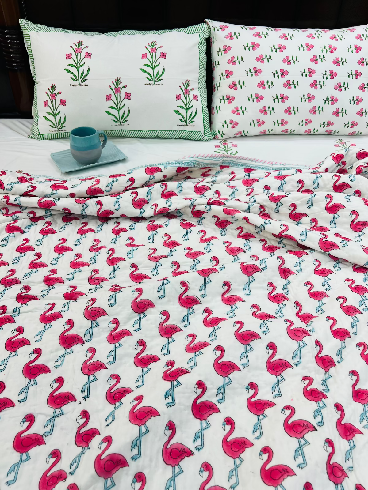 Flamingo patterned bedding set with matching pillows on a bed.